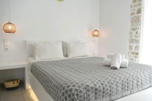 a white bedroom with a bed with white sheets and pillows at Sea View Stone House in Naousa