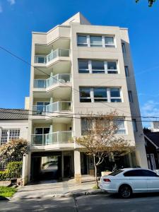 a white car parked in front of a building at Check and Home - San Lorenzo - 2 Huéspedes con Pileta y Cochera in Mar del Plata