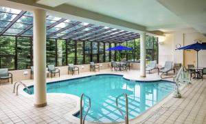 a pool in a hotel with tables and chairs at Hampton Inn Erie-South in Erie