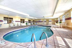 Hampton Inn & Suites West Bend في West Bend: مسبح في غرفة الفندق مع كراسي وطاولة