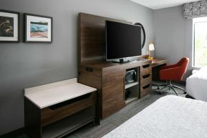 ein Hotelzimmer mit einem TV auf einem Holzschrank in der Unterkunft Hampton Inn & Suites West Bend in West Bend