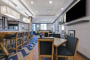 a dining room with tables and chairs and a flat screen tv at Hampton Inn Farmington in Farmington