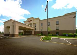 un hotel con bandera americana en un estacionamiento en Hampton Inn North Brunswick NJ, en North Brunswick