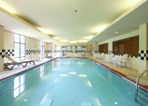 uma grande piscina com cadeiras e mesas brancas em Hampton Inn North Brunswick NJ em North Brunswick