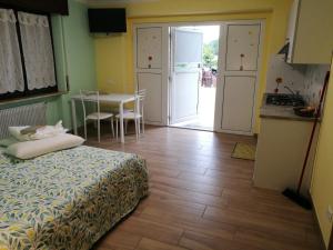 a bedroom with a bed and a kitchen with a table at Colori nel Parco 2 in Cesiomaggiore