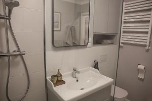 a white bathroom with a sink and a shower at Apartament nad Zegrzem 206 Luksus in Serock