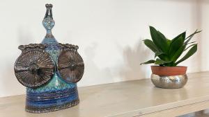 Niebieski wazon siedzący na stole obok doniczki w obiekcie I tre schen w mieście Calasetta