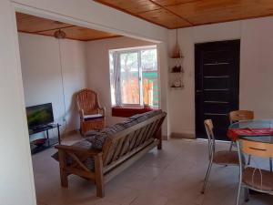 门多萨Acogedora casa para relax en Mendoza的客厅配有长凳、电视和桌子