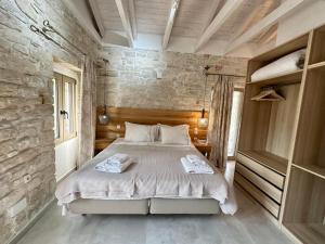 a bedroom with a bed and a stone wall at Villa Nikolas - Secluded and luxurious in Oziás