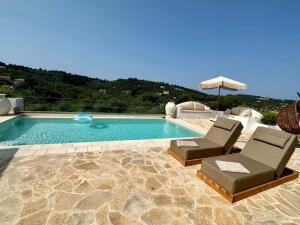 a swimming pool with two chairs and an umbrella at Villa Nikolas - Secluded and luxurious in Oziás