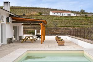 un patio con piscina y pérgola de madera en Feel Discovery Quinta do Muro, en Peso da Régua