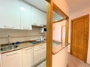 een keuken met witte kasten en een houten deur bij Carabelas-3-12 in Benidorm