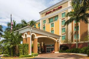 a hotel building with an entrance with palm trees at Hampton Inn & Suites Fort Lauderdale - Miramar in Miramar