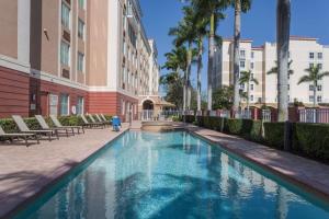 a swimming pool in the courtyard of a building with palm trees at Hampton Inn & Suites Fort Lauderdale - Miramar in Miramar