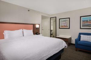 a hotel room with a bed and a blue chair at Hampton Inn Fairfax City in Fairfax