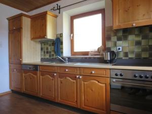 een keuken met houten kasten, een wastafel en een raam bij Haus Erle in Peiting