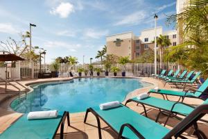 a swimming pool with blue chairs and a building at Homewood Suites Fort Myers Airport - FGCU in Fort Myers