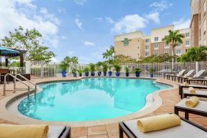 Homewood Suites Fort Myers Airport - FGCU في فورت مايرز: مسبح في فندق مع كراسي جلوس