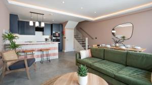 a living room and kitchen with a green couch at Lamington Apartments - Hammersmith in London