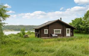 a small wooden cabin in a field with a lake at Amazing Home In Mariager With House Sea View in Mariager