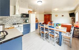 eine Küche mit blauen Schränken und einem Tisch mit Stühlen in der Unterkunft Cozy Home In Vitry-en-charollais With Kitchen in Vitry-en-Charollais
