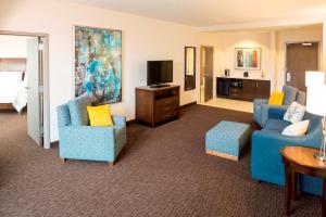 Sala de estar con 2 sillas azules y TV en Hilton Garden Inn Sioux Falls Downtown en Sioux Falls