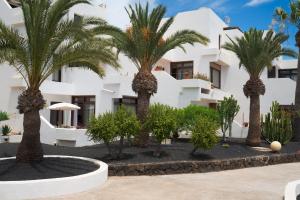 een groep palmbomen voor een gebouw bij Lanzarote Beach Apartments, CASA BRUNA in Costa Teguise