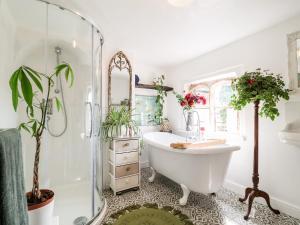 baño con bañera, espejo y plantas en Harmony Cottage en Bungay