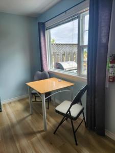 1 mesa y 2 sillas en una habitación con ventana en Baywatch Lighthouse Cottages & Motel en Brackley Beach