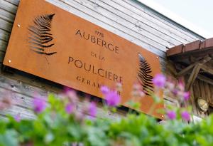 um sinal na lateral de um edifício com flores em Auberge De La Poulcière em Gérardmer