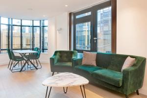 un soggiorno con divano verde e tavolo di Brentford Apartments by Charles Hope a Brentford