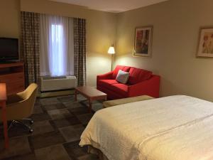 um quarto de hotel com uma cama e uma cadeira vermelha em Hampton Inn Garden City em Garden City