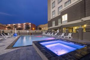 ein großer Pool mit Stühlen und ein Gebäude in der Unterkunft Hampton Inn & Suites Galveston in Galveston