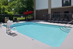 una gran piscina con sombrilla y sillas rojas en Hampton Inn Greensboro East / McLeansville, en McLeansville