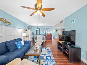 een woonkamer met een blauwe bank en een plafondventilator bij Holiday Surf and Racquet Unit 510 in Destin