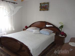 a bedroom with a large wooden bed with white sheets at Apartment Jelić in Senj