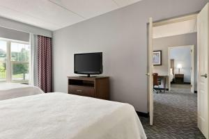 a hotel room with a bed and a flat screen tv at Homewood Suites by Hilton Harrisburg East-Hershey Area in Harrisburg