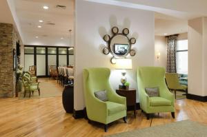 een woonkamer met twee groene stoelen en een spiegel bij Hampton Inn Hickory in Hickory
