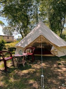 姆热日诺Camping Rogowo的草顶帐篷,配有两把椅子和一张桌子