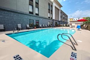 une grande piscine avec des chaises et un bâtiment dans l'établissement Hampton Inn Houston Baytown, à Baytown