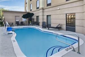 una piscina en un hotel con sillas y mesas en Hampton Inn Hinesville en Hinesville