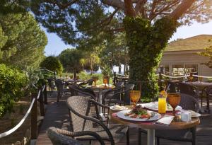 a patio with tables and chairs with food and drinks at PortoBay Falesia in Albufeira
