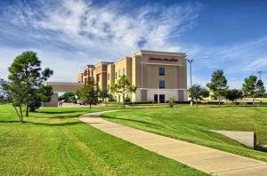 a building with a walkway in front of a park at Hampton Inn & Suites Houston Rosenberg in Rosenberg