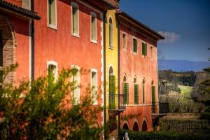 a large red building with green shutters on it at Villa Clementina - Prosecco Country Hotel in San Pietro di Feletto
