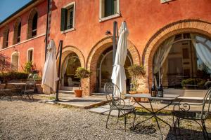 a table and chairs with umbrellas in front of a building at Villa Clementina - Prosecco Country Hotel in San Pietro di Feletto