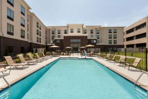 a swimming pool with lounge chairs and a building at Homewood Suites by Hilton Huntsville-Downtown in Huntsville