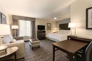 a hotel room with a bed and a couch and a table at Homewood Suites by Hilton Huntsville-Downtown in Huntsville