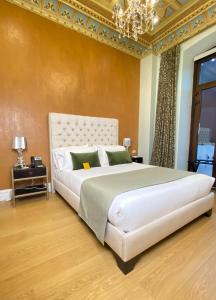 ein Schlafzimmer mit einem großen weißen Bett und einem Kronleuchter in der Unterkunft Itza Hotel Boutique Internacional in Cuenca
