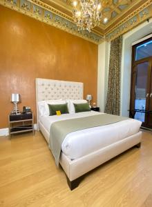 a bedroom with a large white bed with a chandelier at Itza Hotel Boutique Internacional in Cuenca