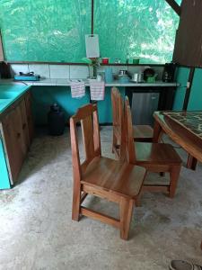 a kitchen with two wooden chairs and a table at Corcovado Guide House in Barrigones
